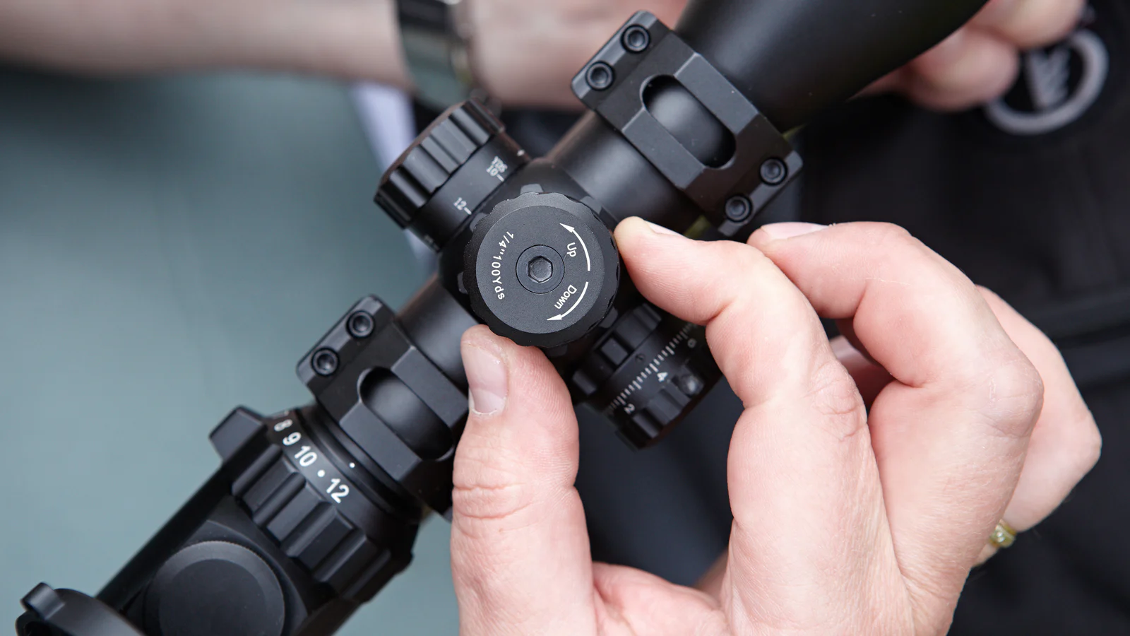A shooter making a precise adjustment to a riflescope turret